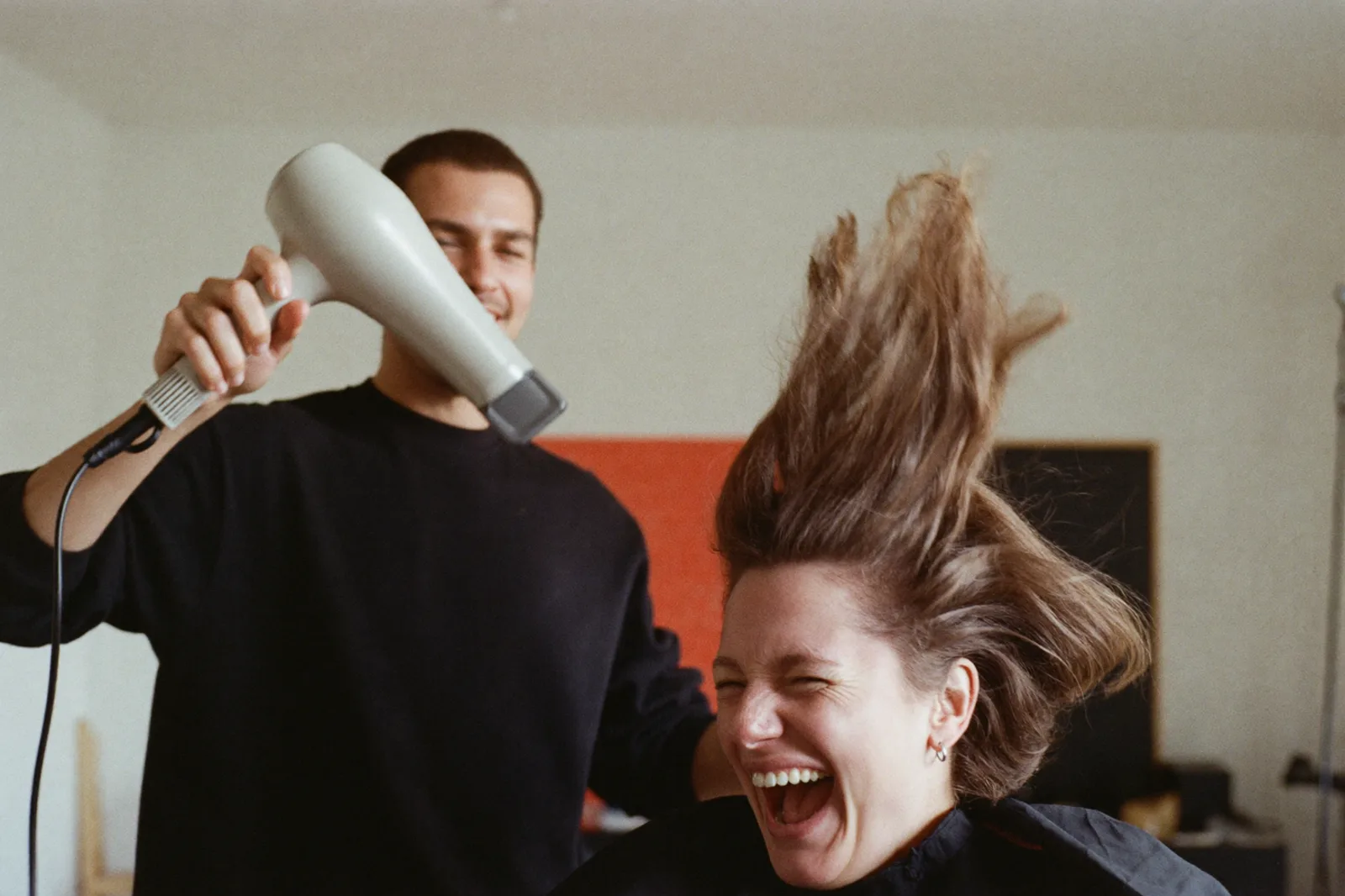 Föhnen im Salon, Kundin lacht, Haar fliegt (Symbolfoto)
