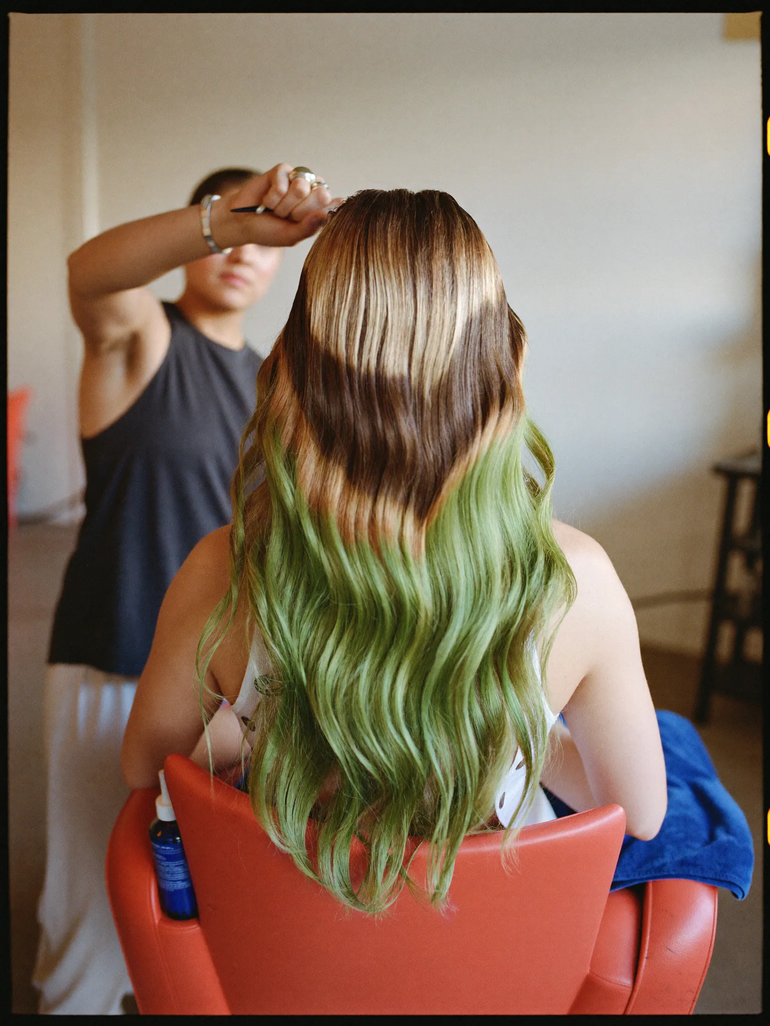 Coloration im Salon: Colorist arbeitet an langem, farbig gesträhntem Haar (Symbolfoto)